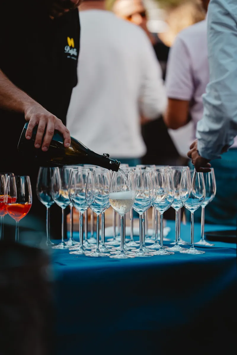 Service de bulles : une bouteille versée dans une rangée de flûtes sur nappe bleue