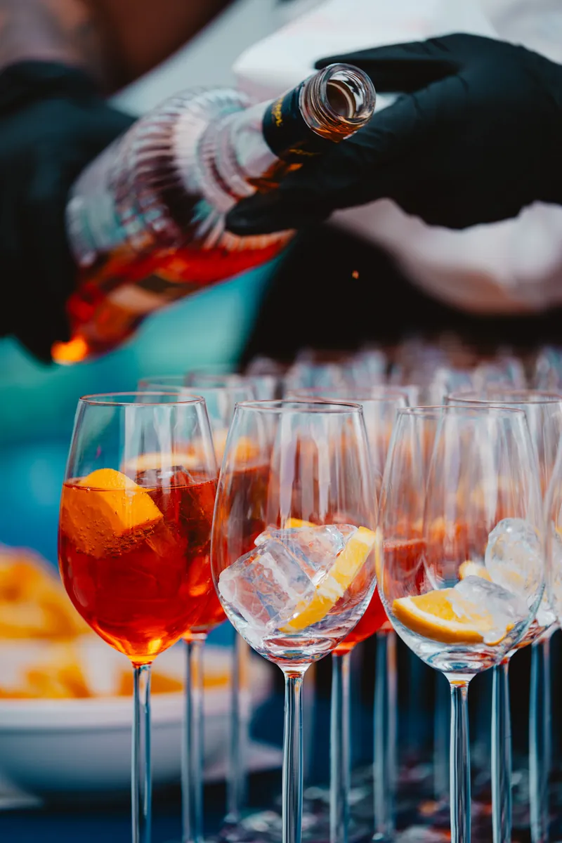 Verres de spritz alignés, glace et tranche d'orange, lumière du jour