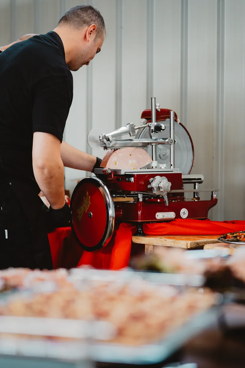 Trancheuse rouge à volant : un cuisinier tranche la charcuterie devant les invités