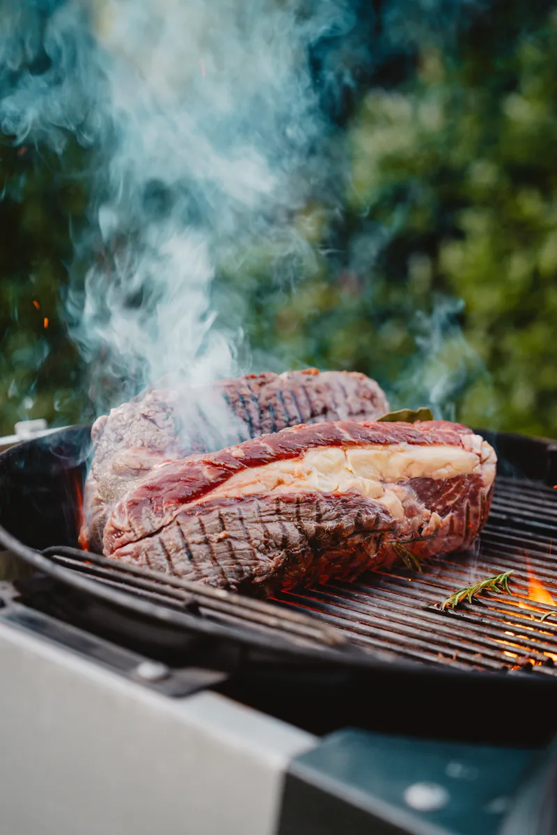 Pièce de viande sur le gril, fumée et romarin, en plein air