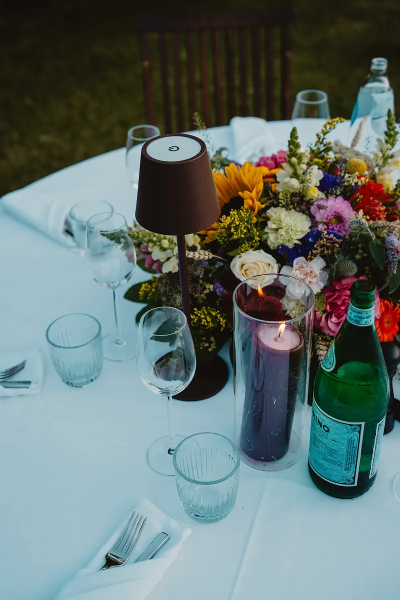 Table de jardin : lampe, bouquet de fleurs, bougie et eau pétillante