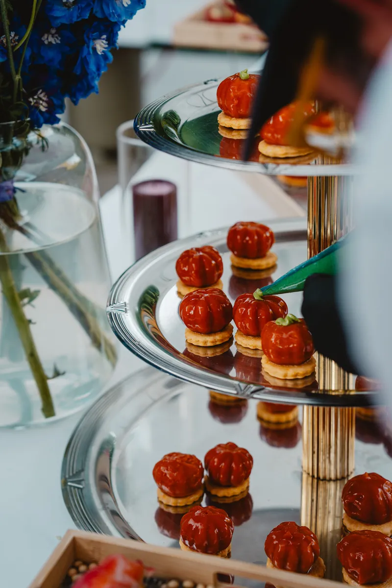 Tartelettes de tomates sur présentoirs à étages, fleurs bleues en arrière-plan