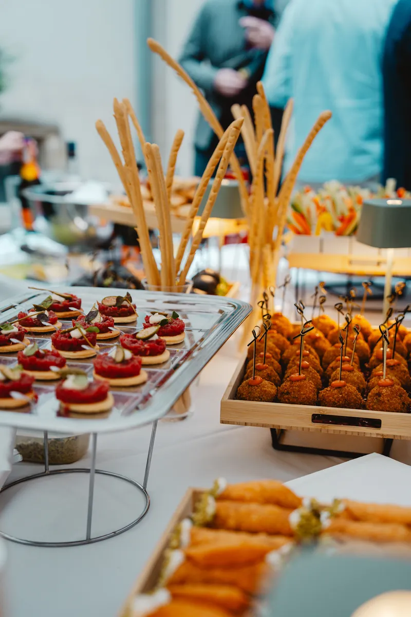 Présentoirs de bouchées, tartelettes de tartare et gressins sur une table de réception